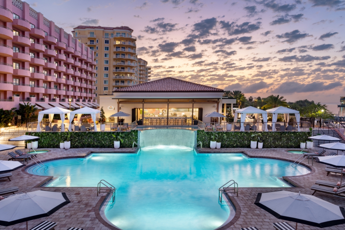 a pool with a building and umbrellas