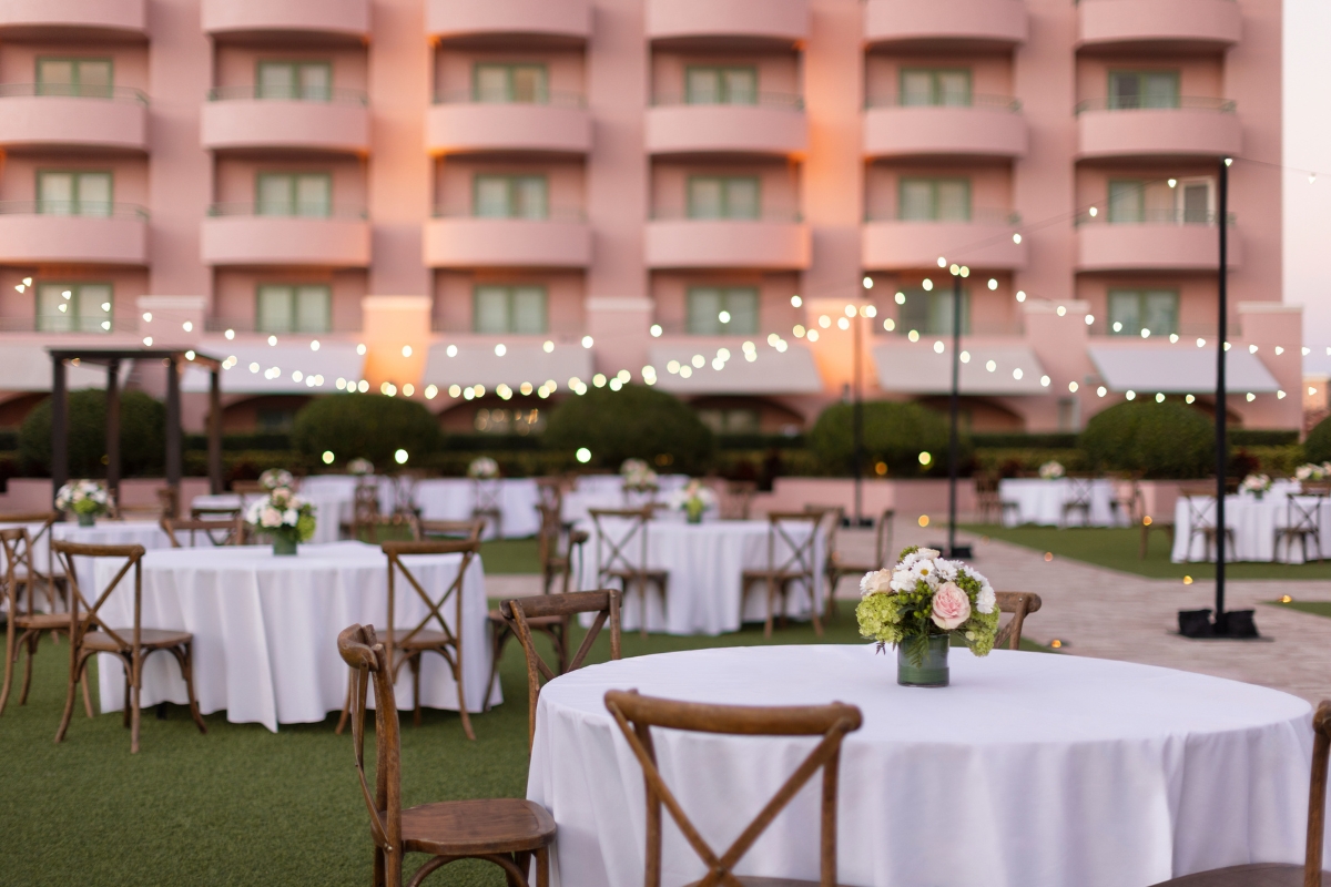a group of tables and chairs outside with a pink building in the background