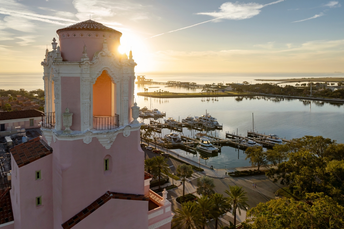 a pink tower with a pier and boats in the background