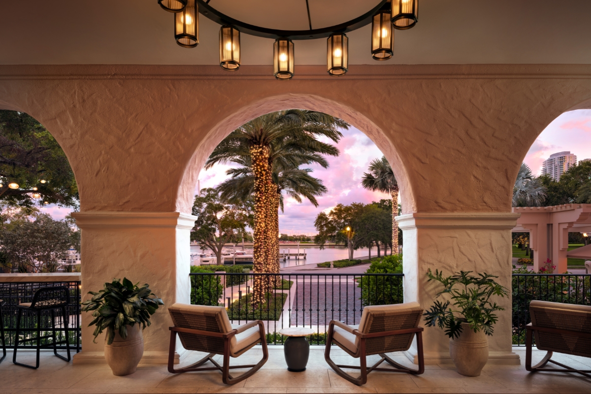chairs in a room with a balcony and palm trees