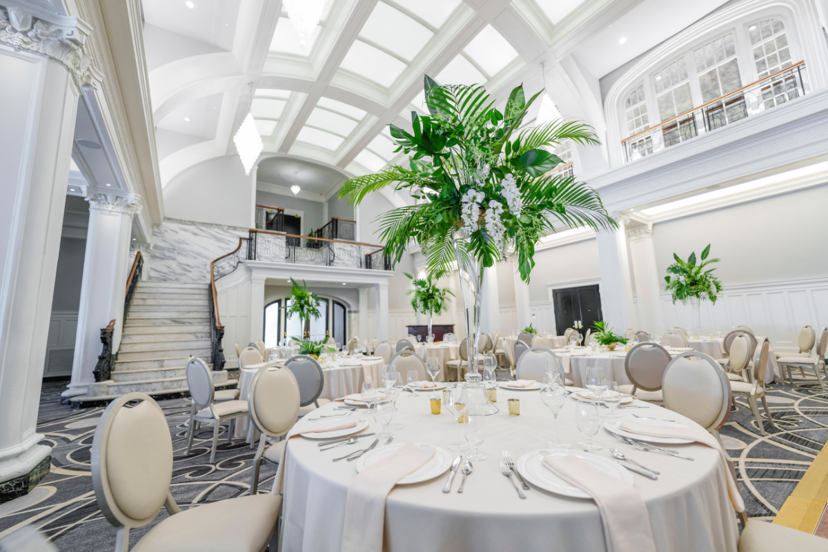 a room with tables and chairs and a tall vase of flowers