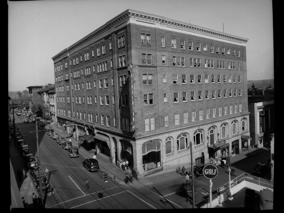 a large brick building with a street and cars on the side
