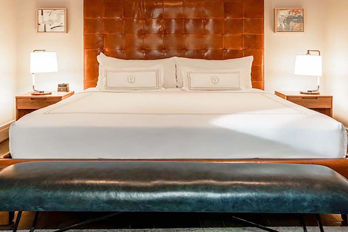 a bed with a leather headboard and a lamp