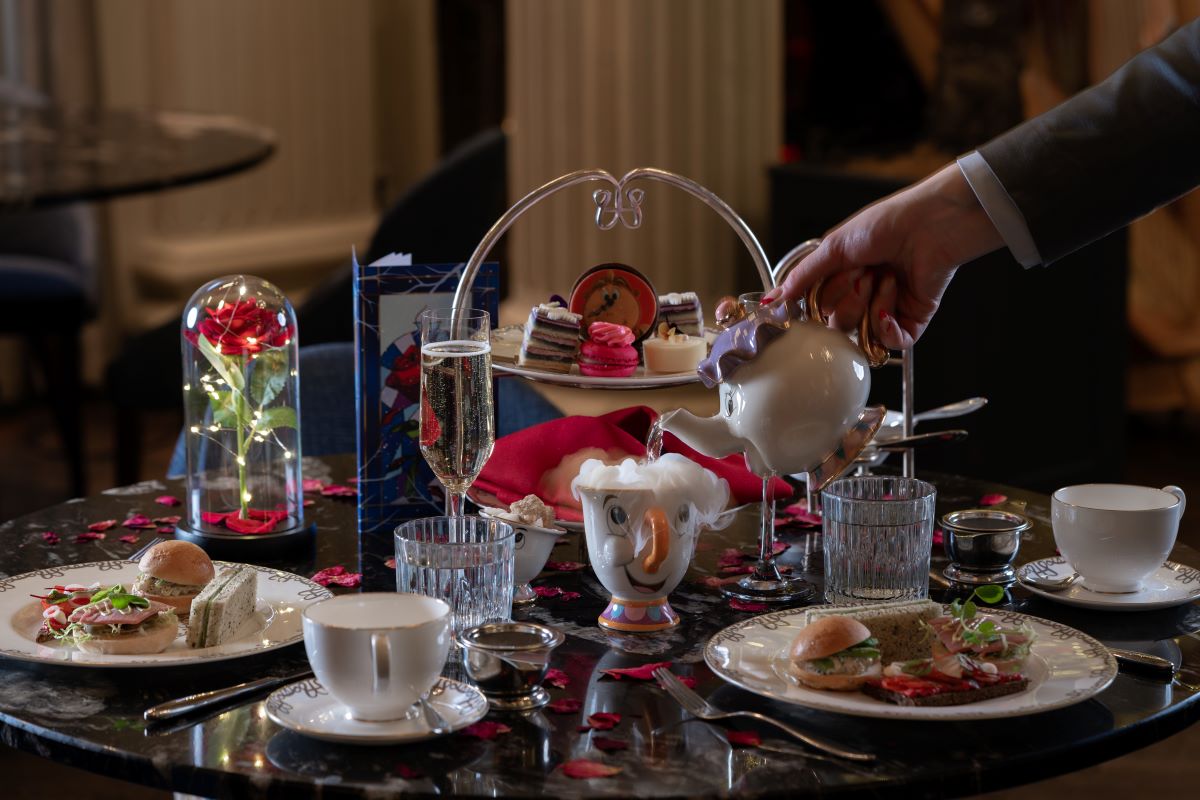 a hand pouring tea into a teapot on a table