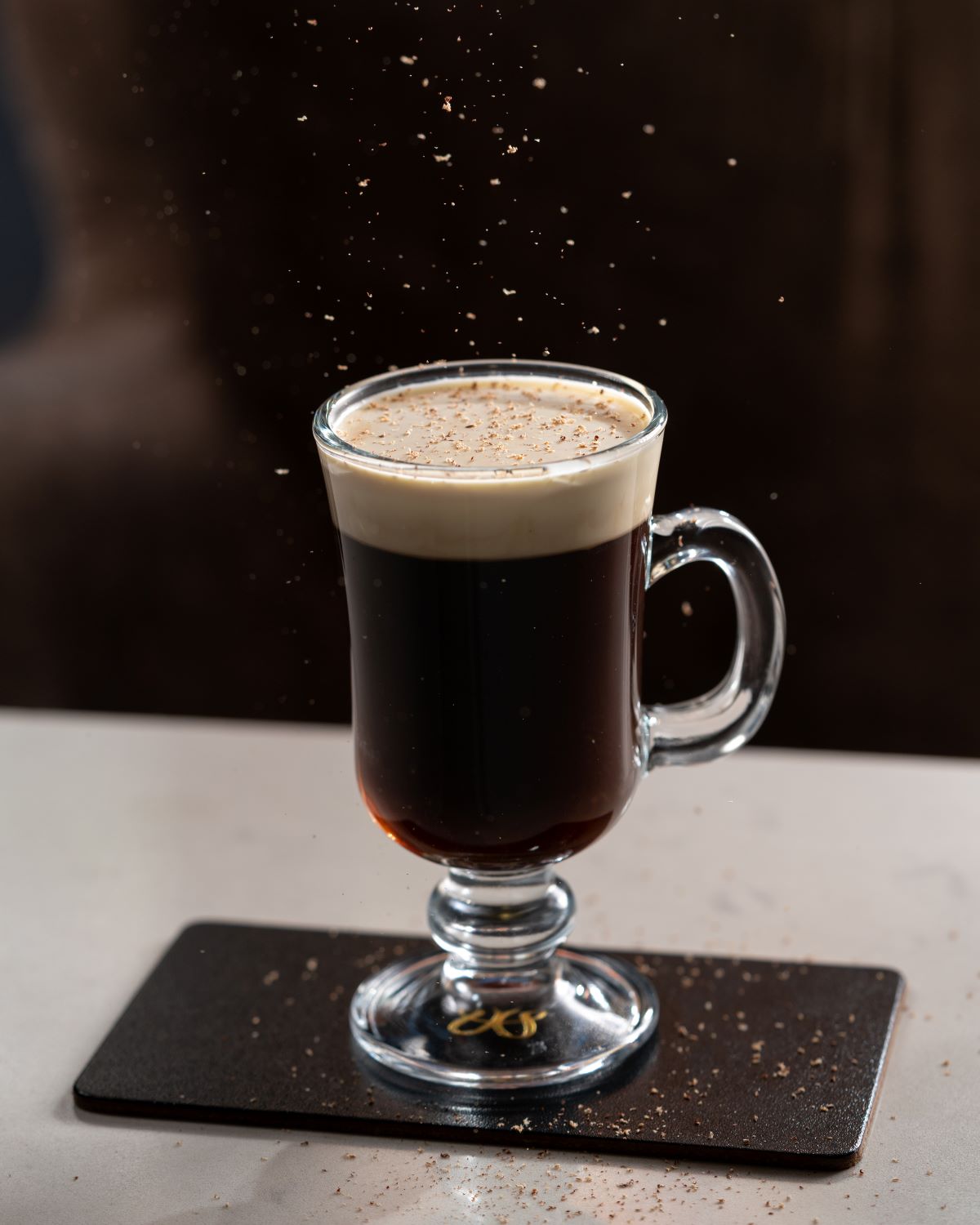 a glass of coffee with brown liquid and foam