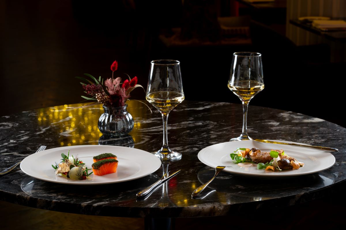 a table with plates of food and wine glasses