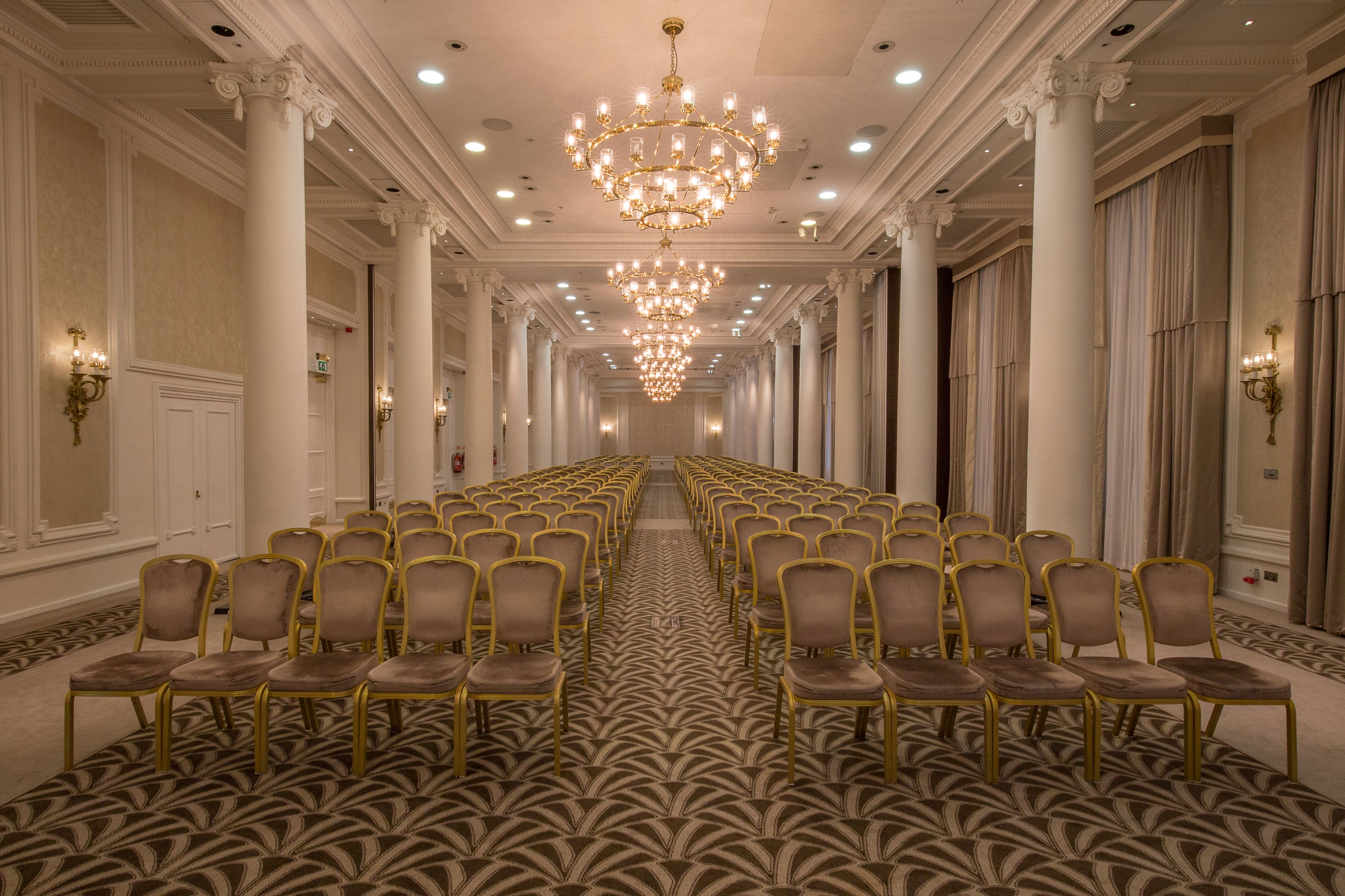 a room with rows of chairs and chandeliers