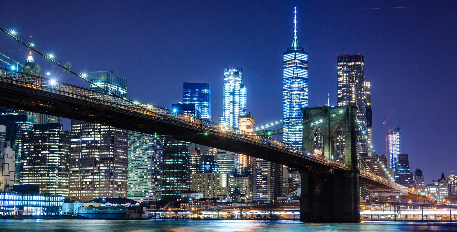 a bridge over water with city skyline at night