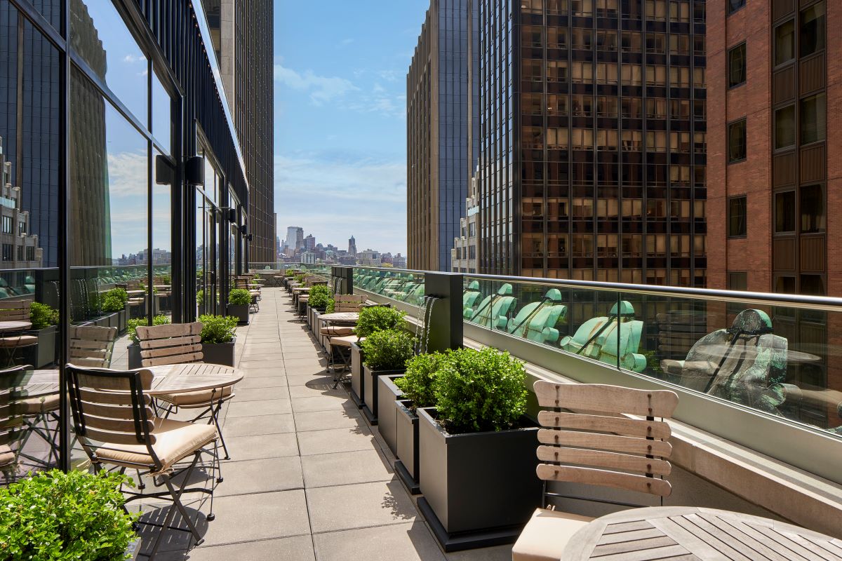 a balcony with chairs and tables and plants