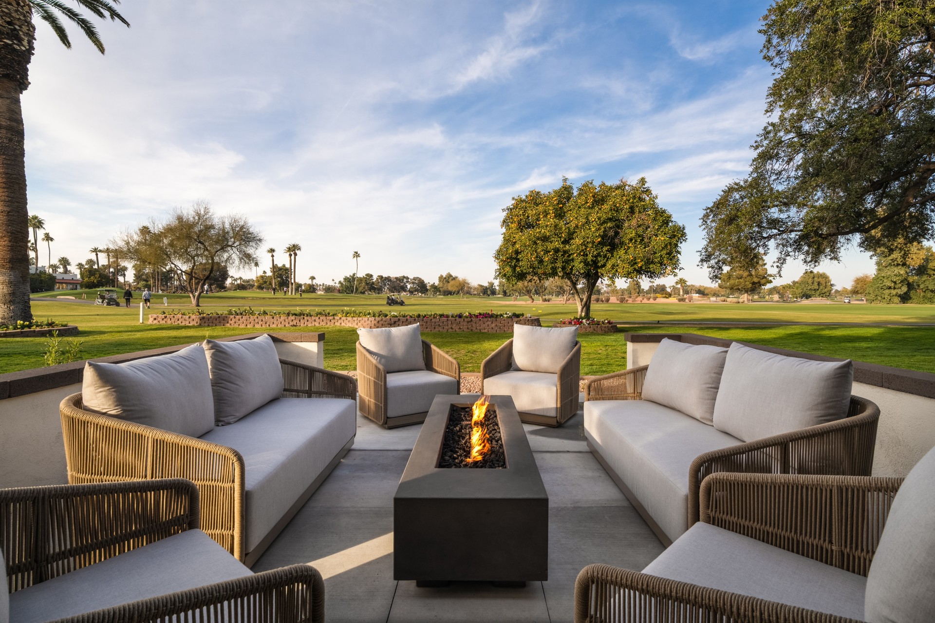 a patio with a fire pit and white couches