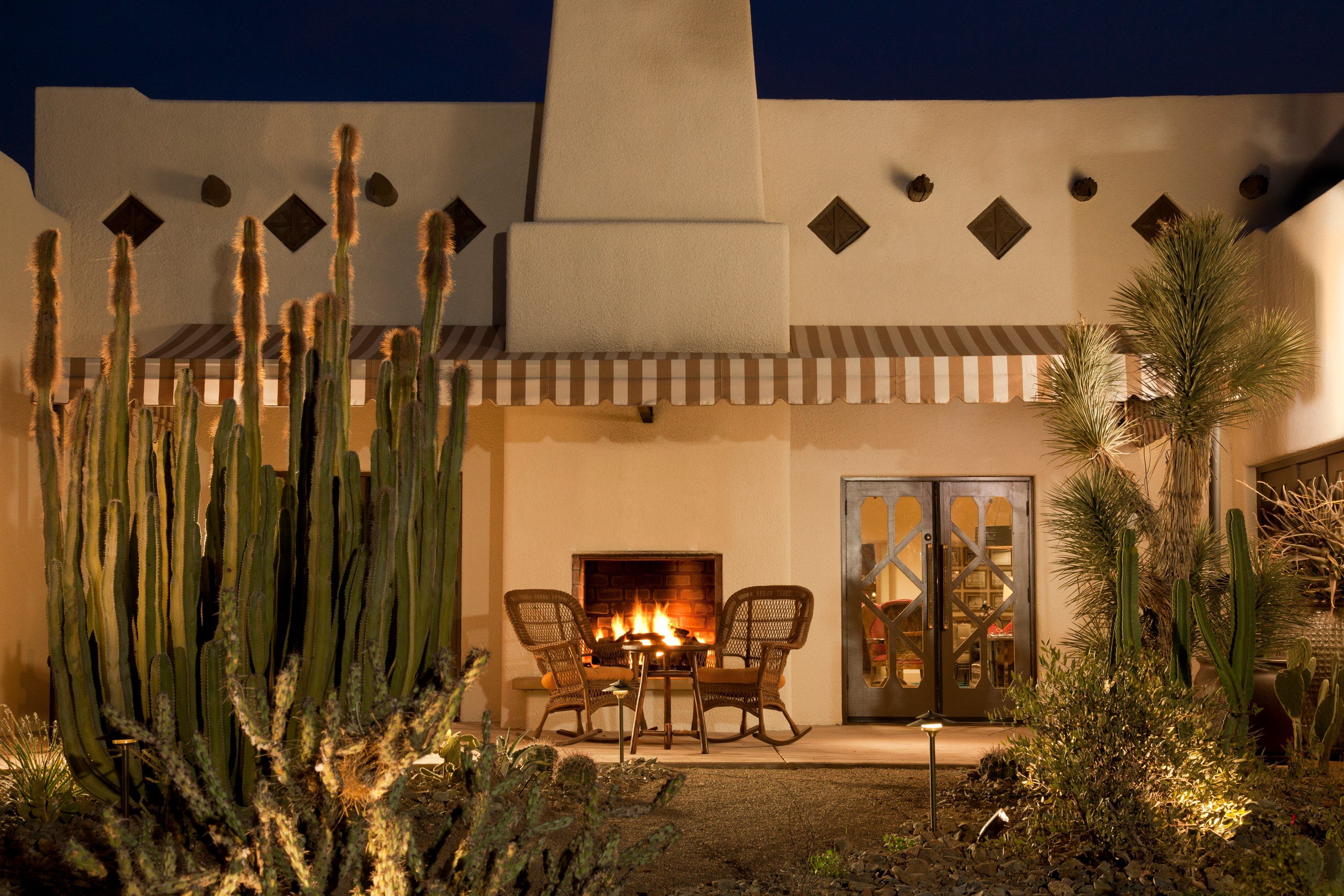a patio with chairs and a fire pit in front of a house