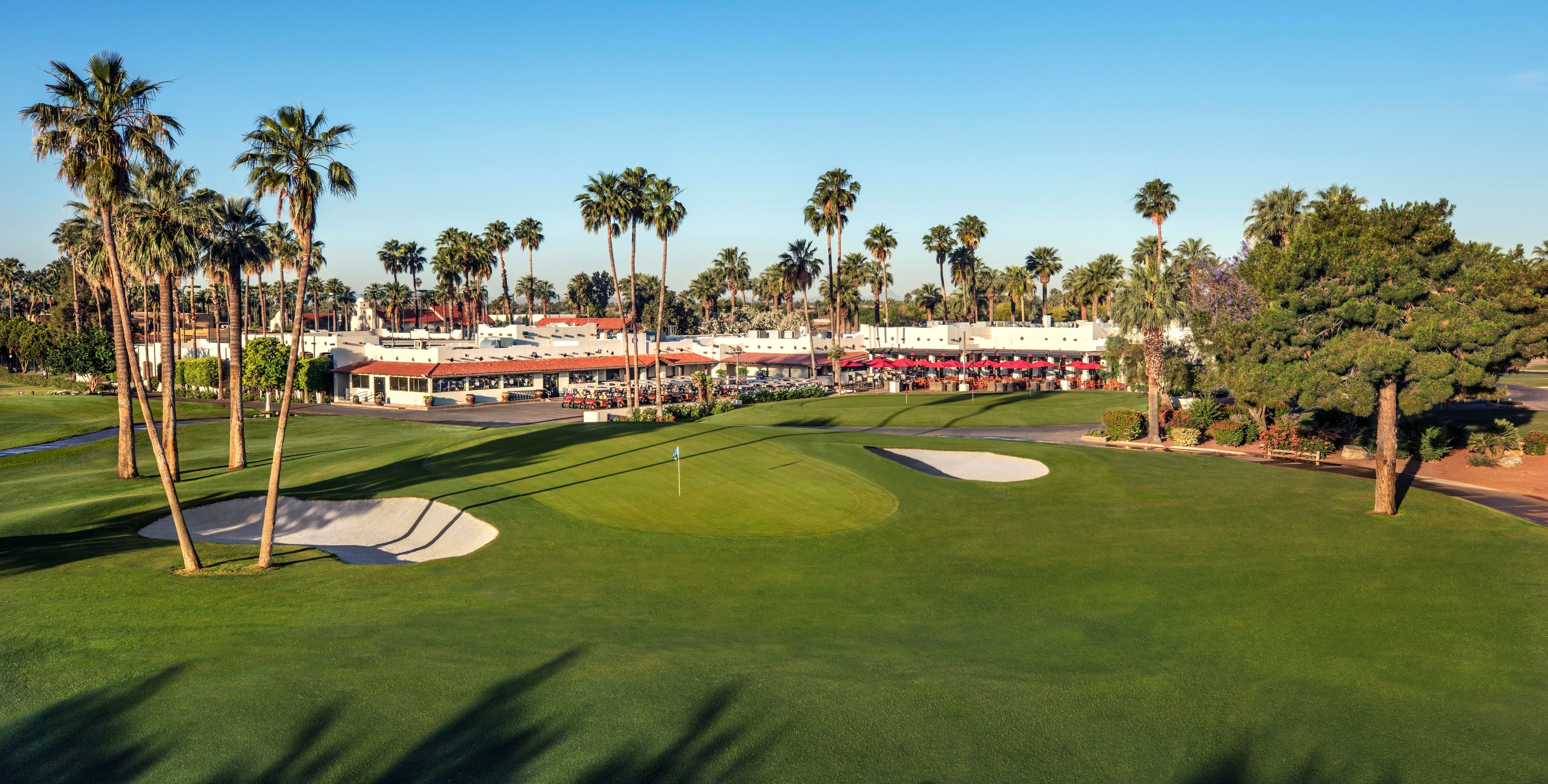 a golf course with palm trees and buildings