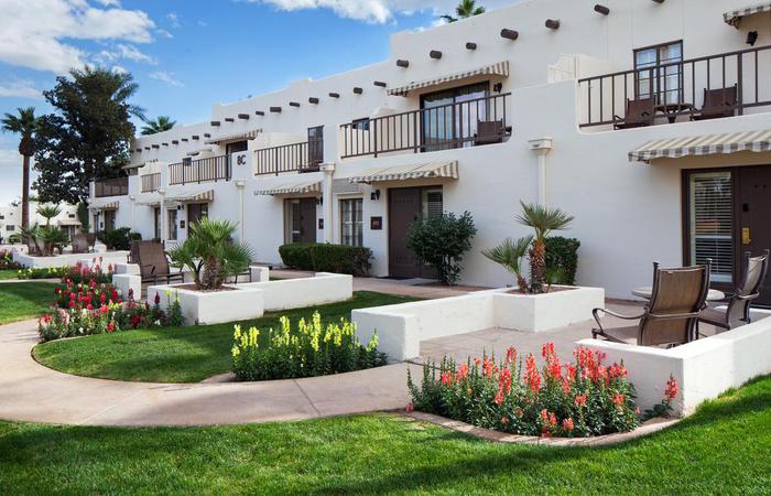 a white building with a lawn and plants