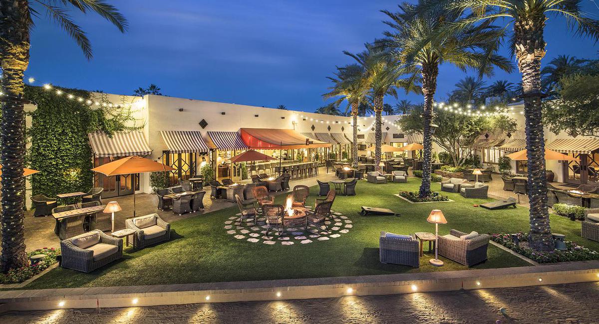 a building with a fire pit and palm trees