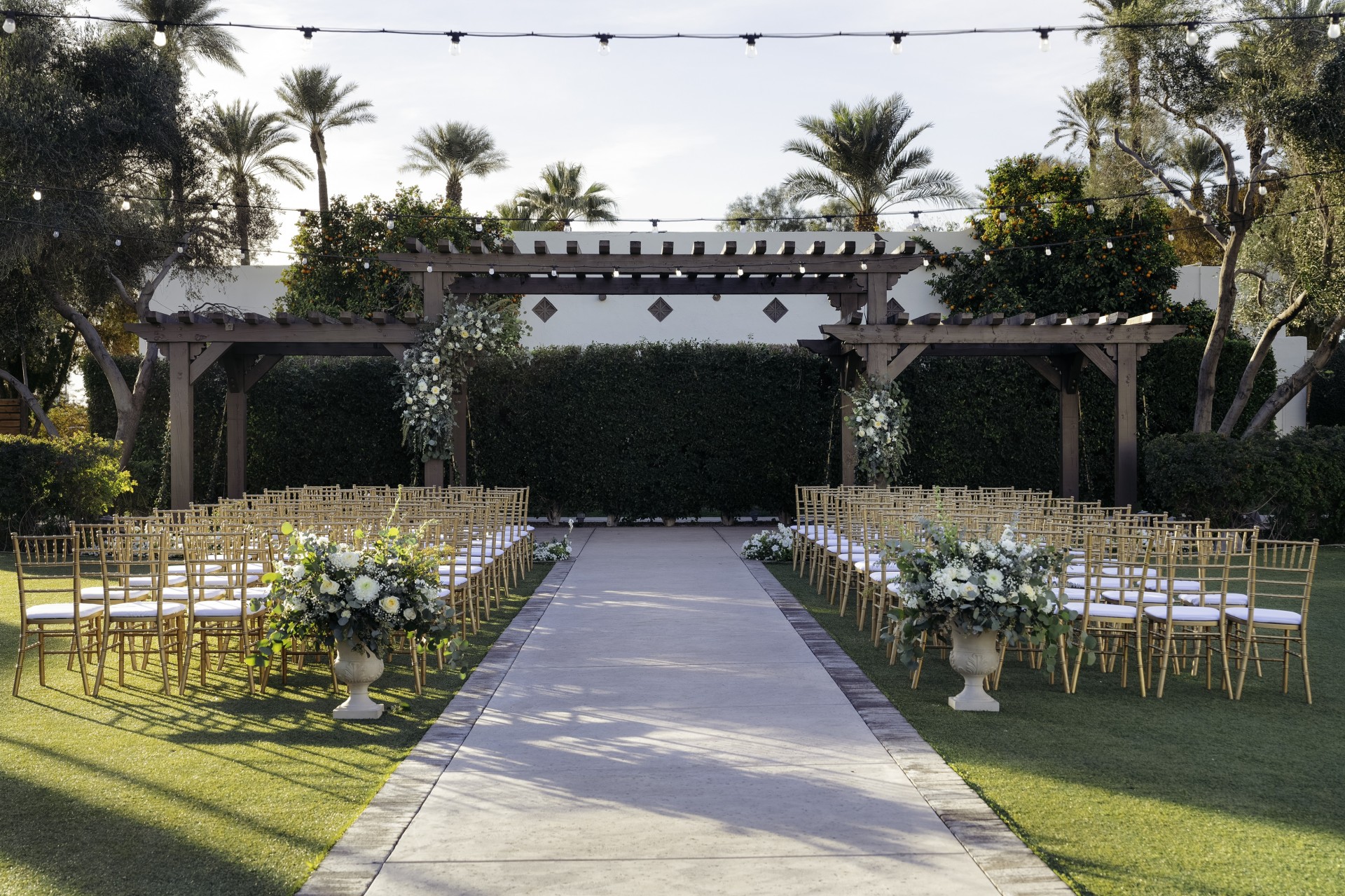 a walkway with chairs and flowers in front of a building