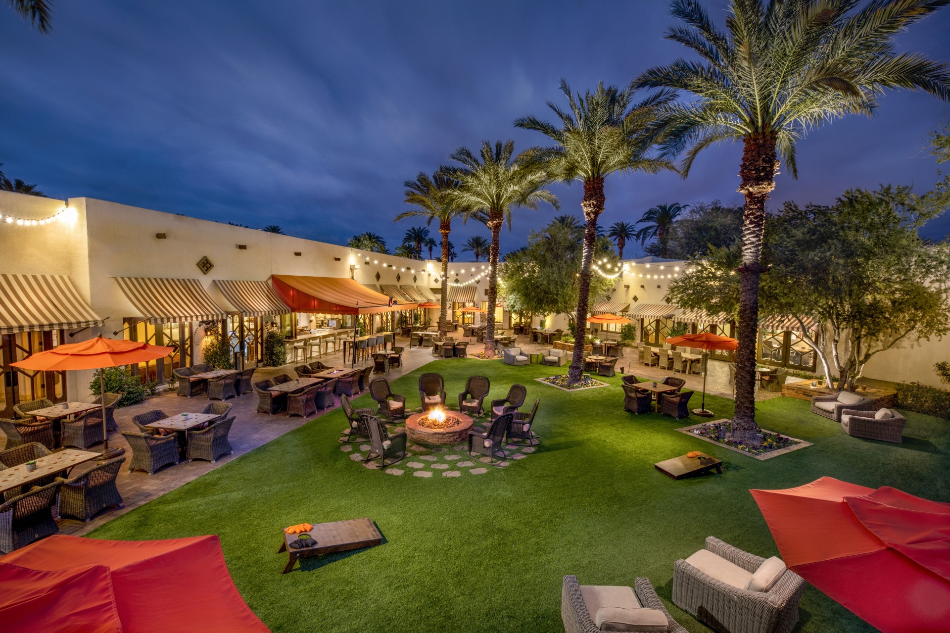 a patio area with chairs and tables and palm trees