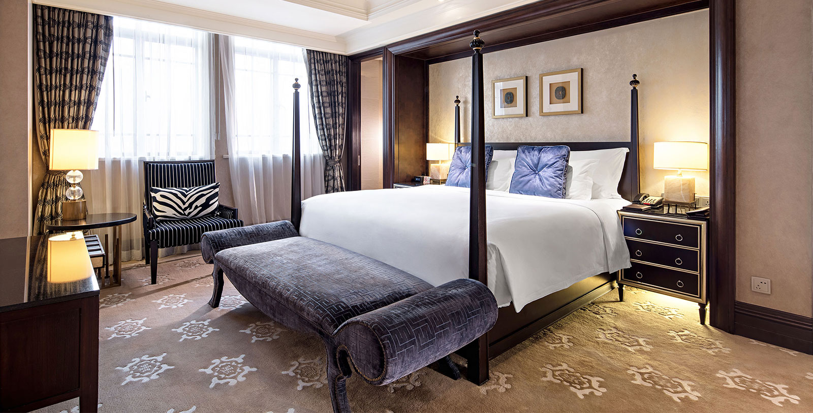 a bed with a four poster bed and a bench in a room