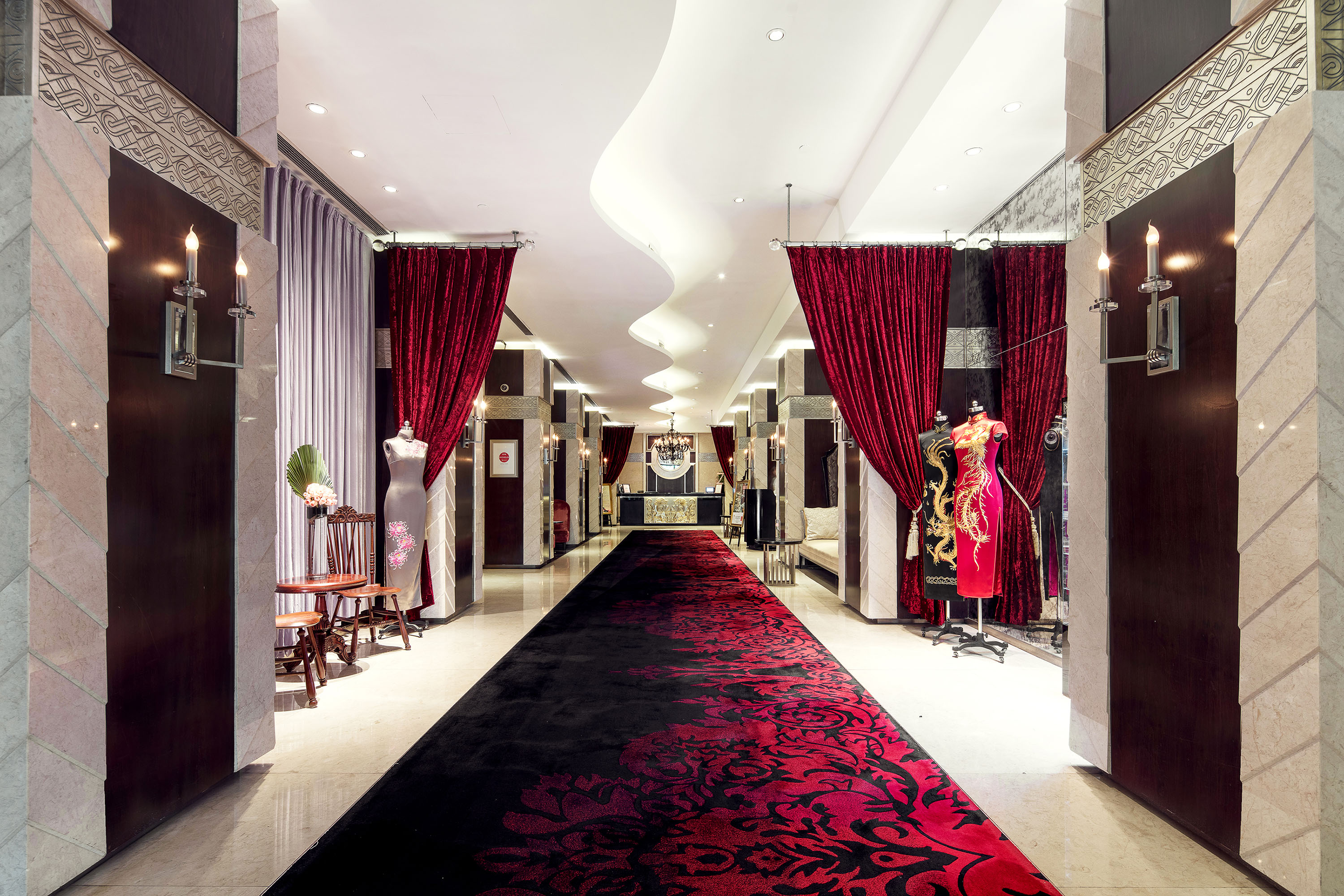 a long hallway with red curtains and mannequins