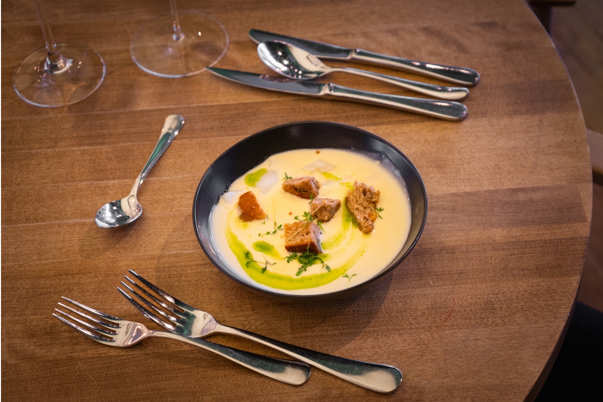 a bowl of soup with silverware on a table