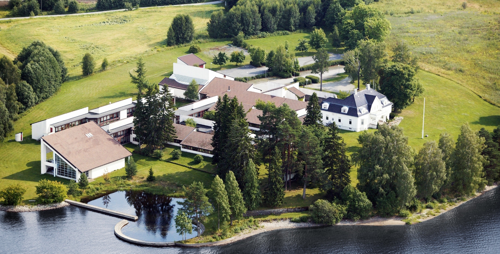 a large white building surrounded by trees and a body of water