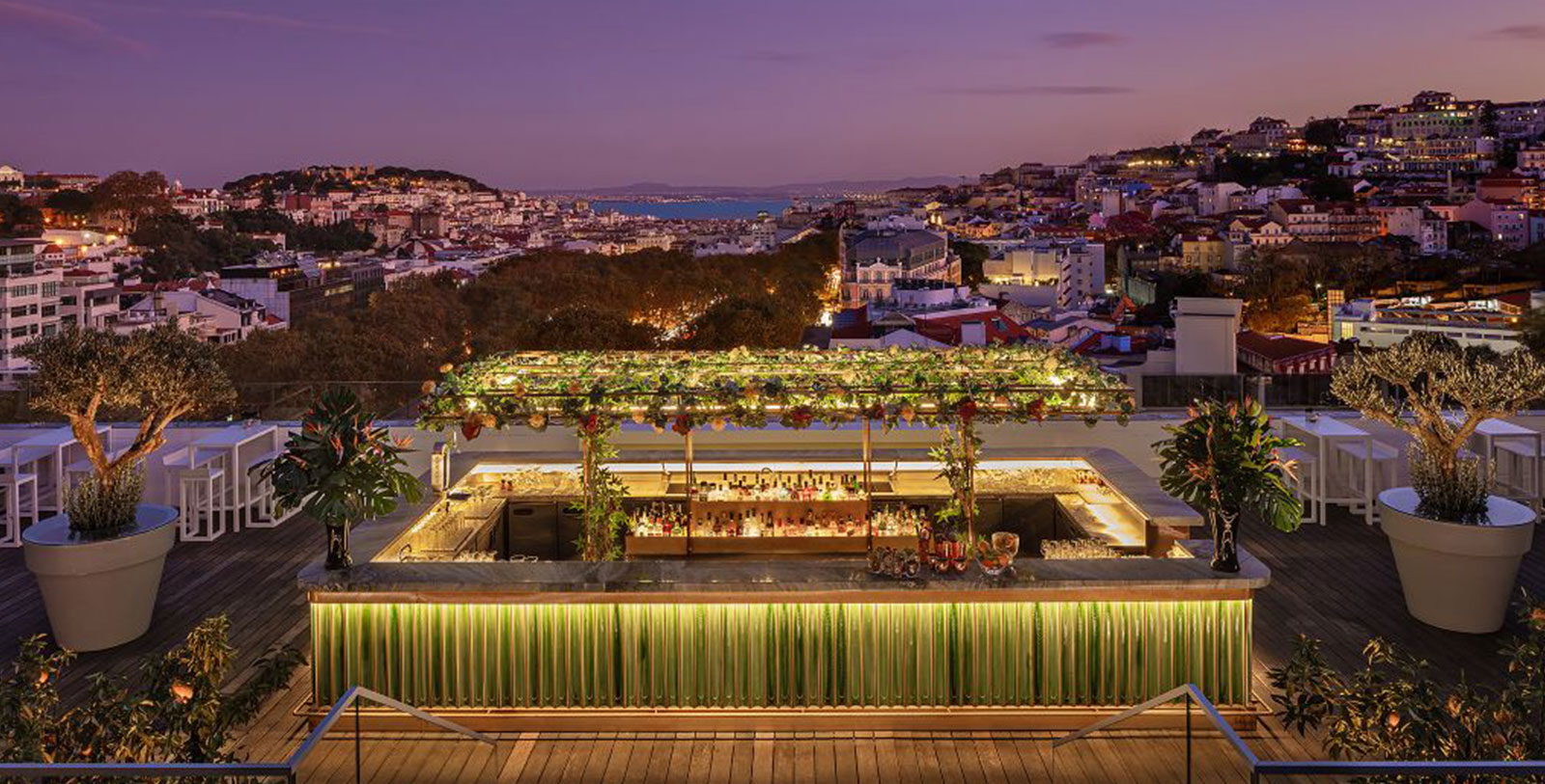 a rooftop bar with a view of a city and water