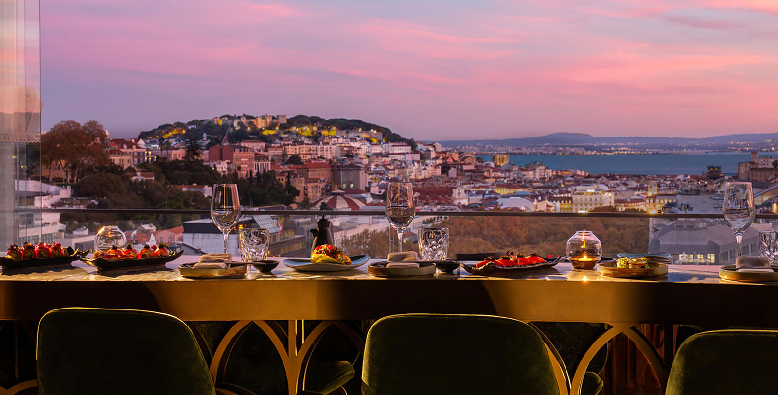 a table with plates and glasses on it with a view of a city in the background