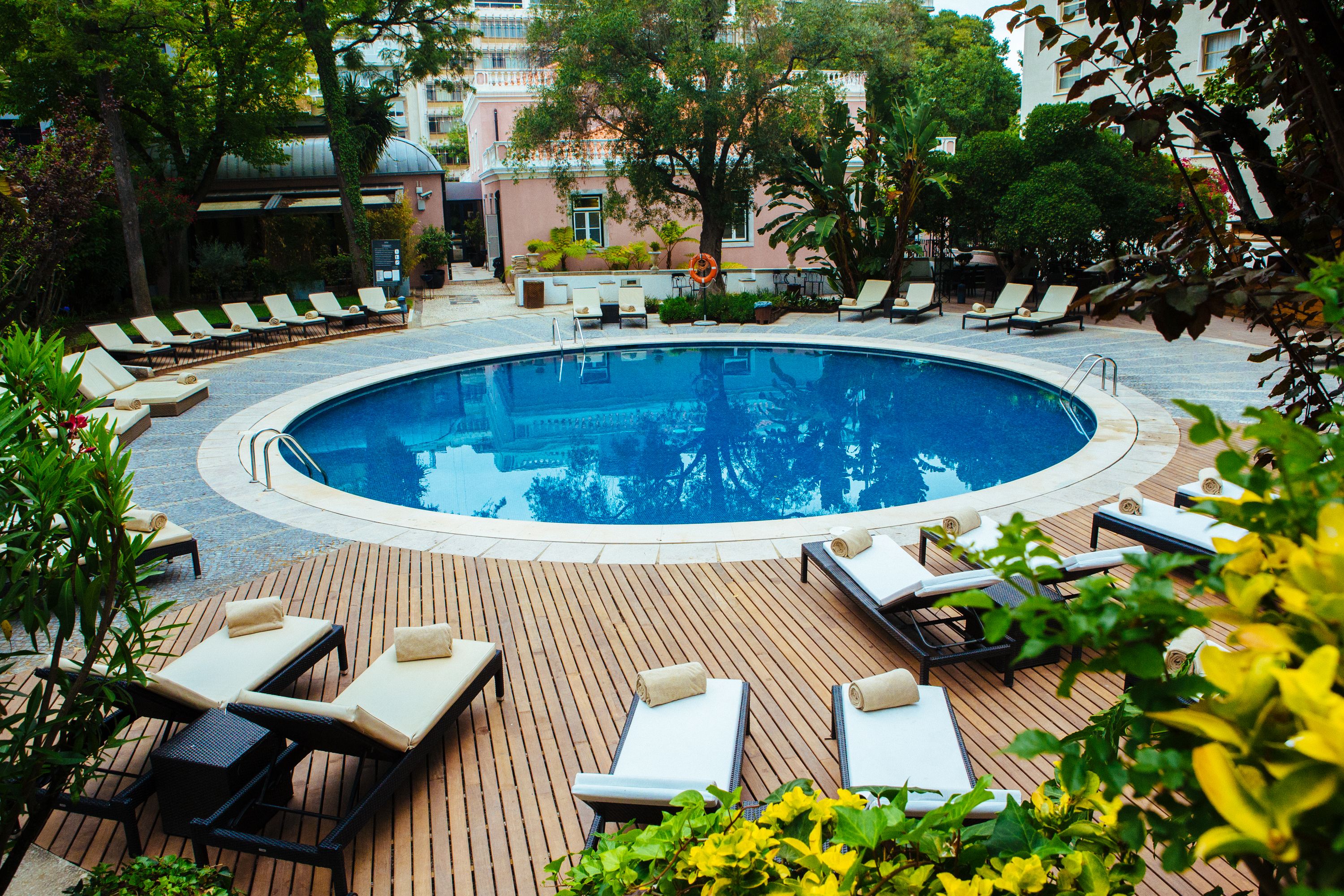 a pool with lounge chairs and trees