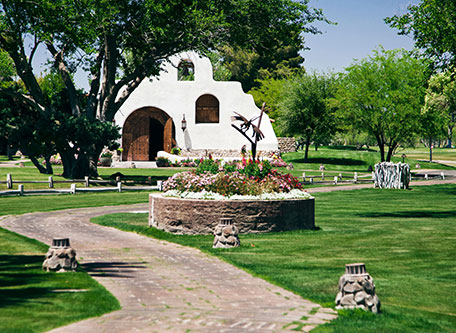 a white building with a flower bed in front of a garden