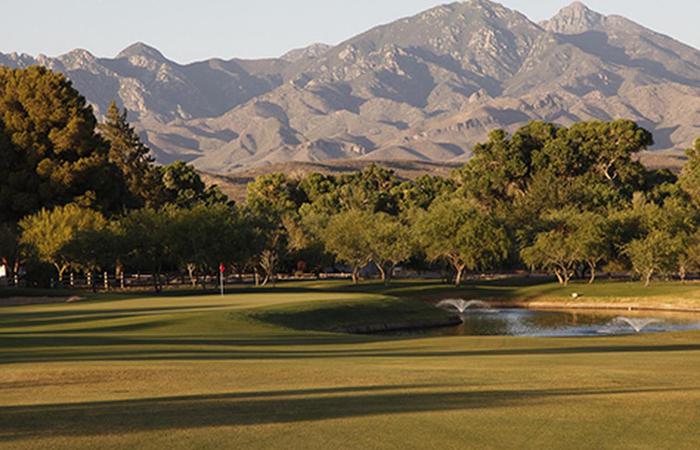 a golf course with a lake and mountains in the background