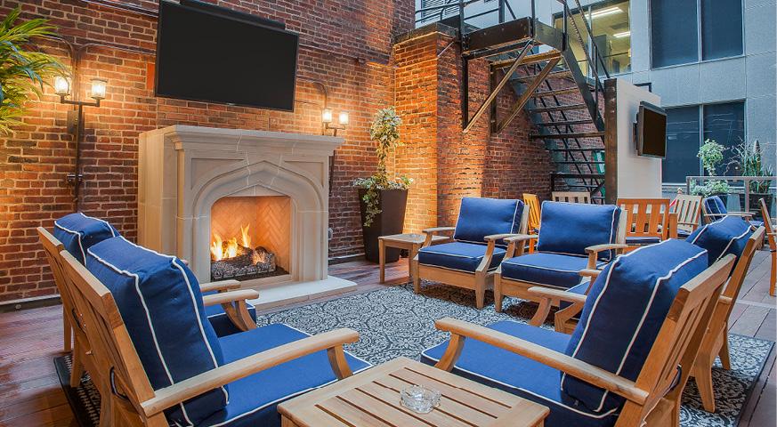 a patio with blue chairs and a fire pit