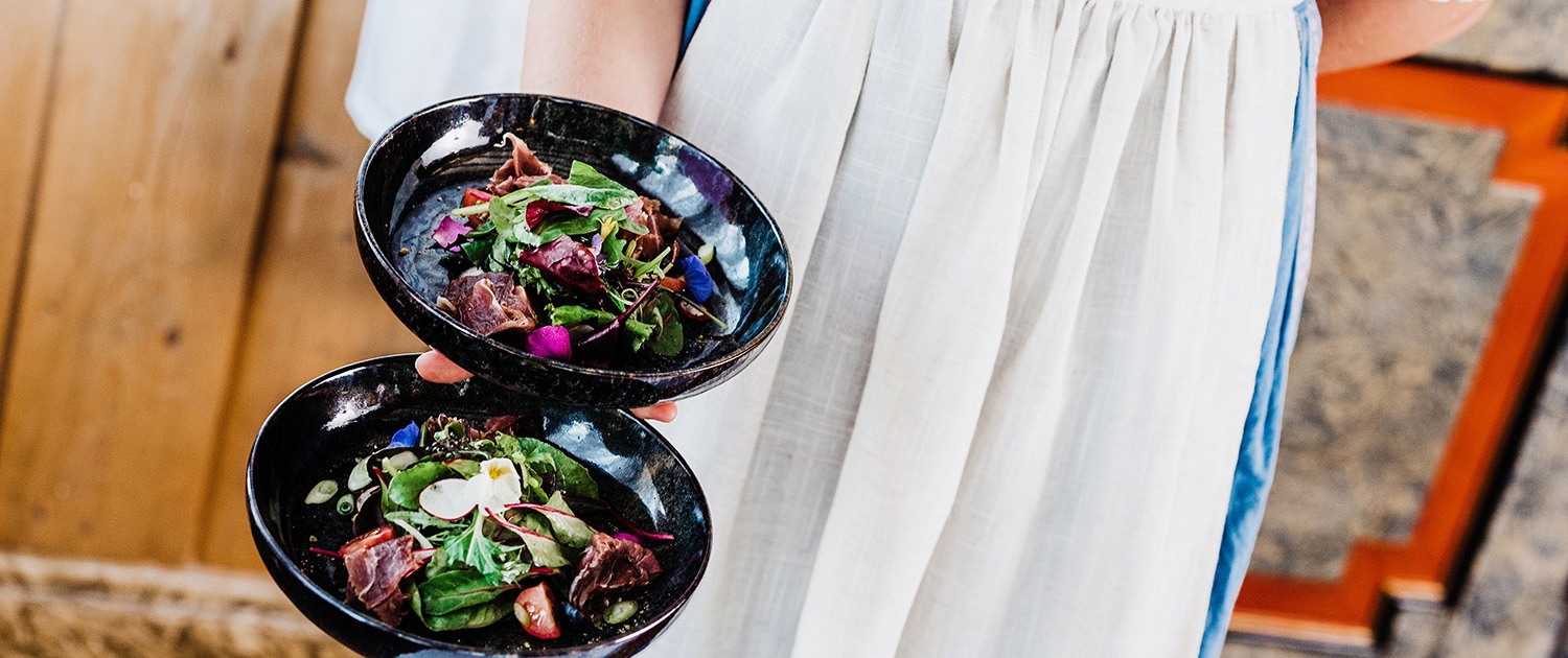 a person holding two plates of salad