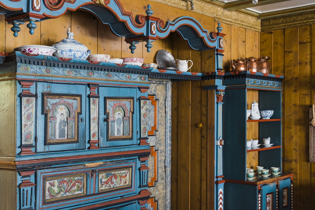 a blue and red painted cupboard with a shelf above it