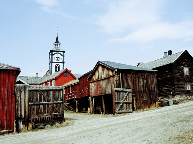 a wooden buildings with a clock tower in the background