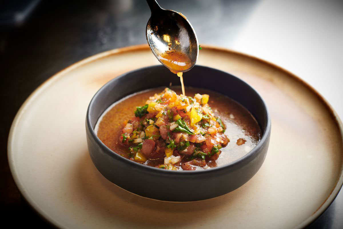 a spoon pouring liquid into a bowl of soup