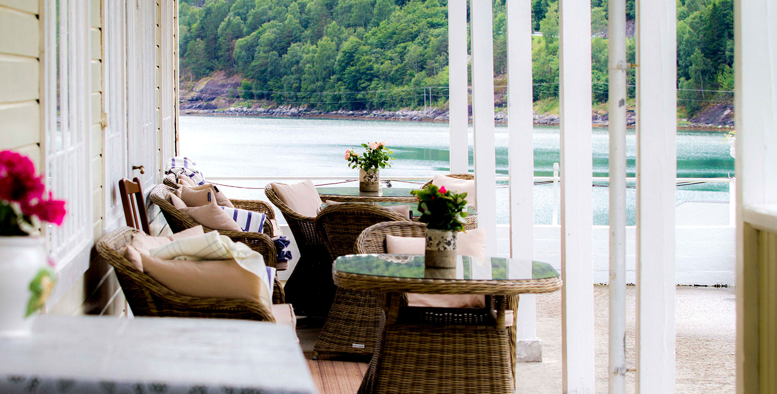 a table and chairs on a porch with a lake in the background