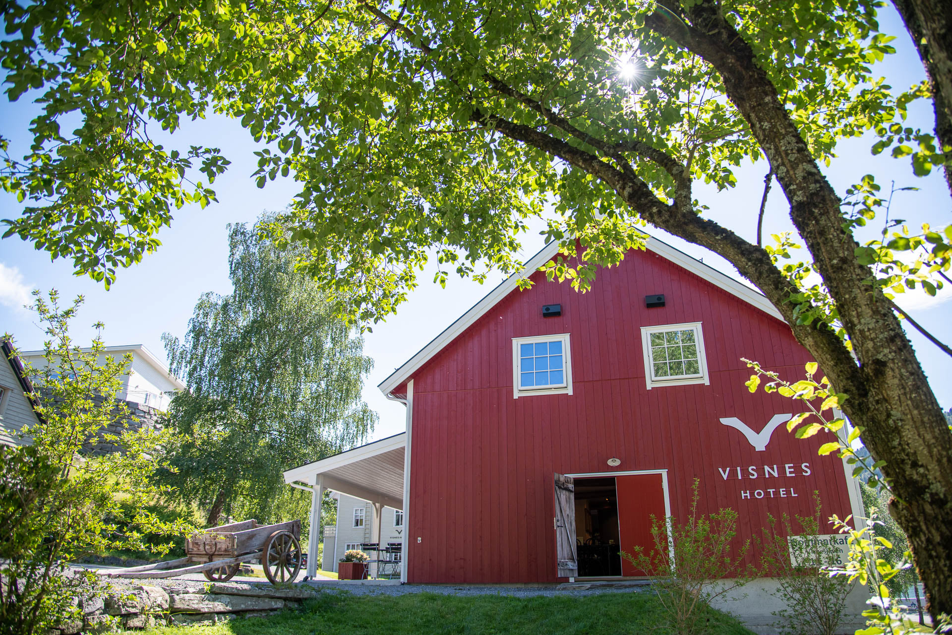 a red barn with a white roof and a wagon on the side