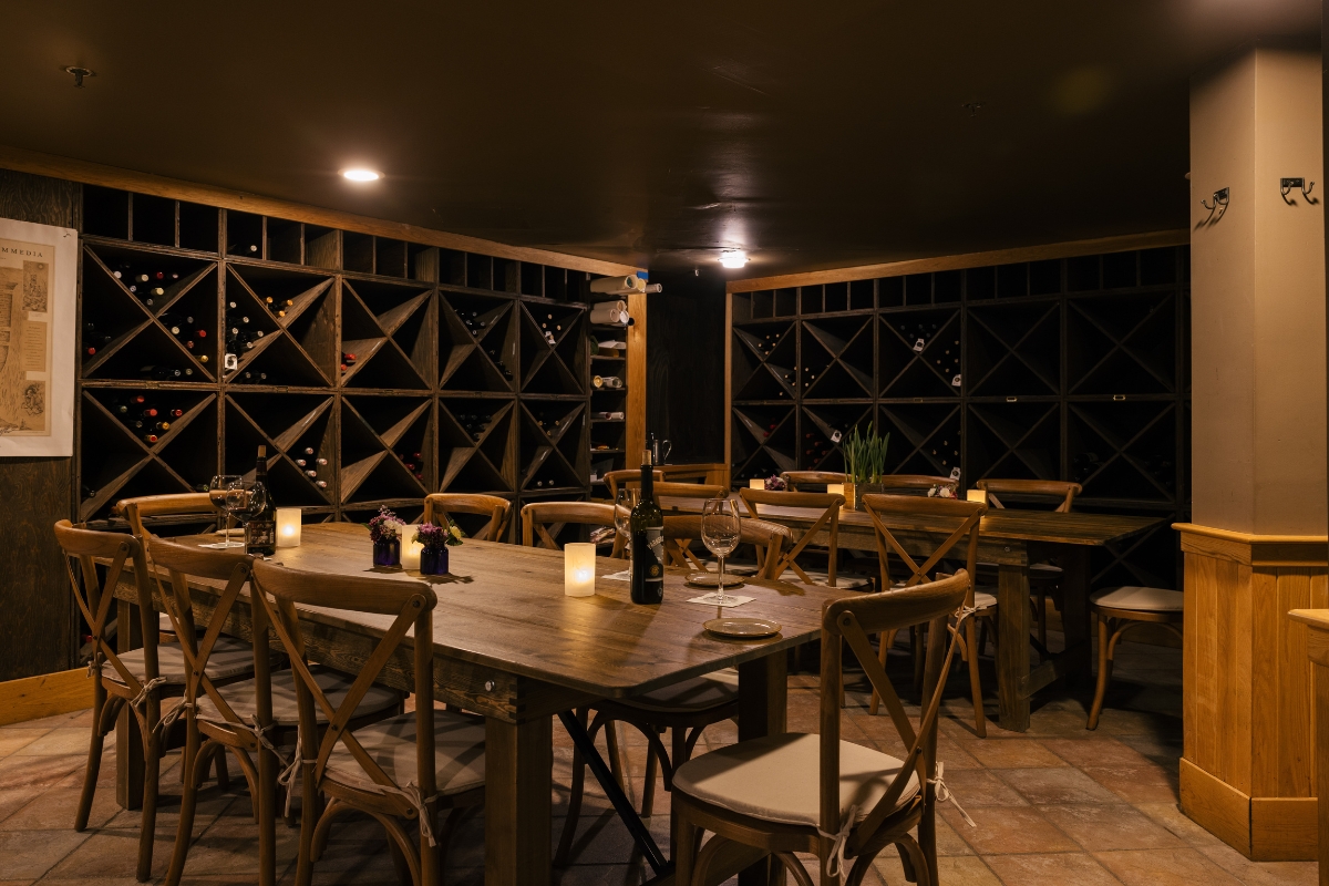 a table with wine glasses and candles in a room with shelves