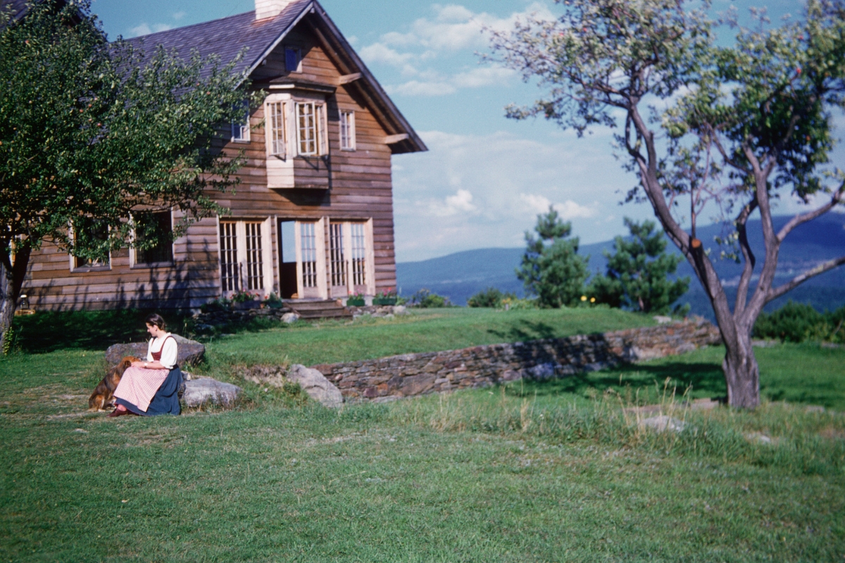 a woman sitting on a rock in front of a house