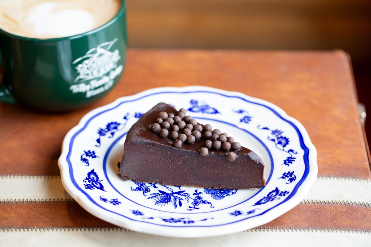a piece of chocolate cake on a plate with a cup of coffee