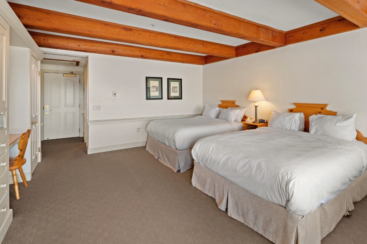 a room with two beds and a wooden ceiling