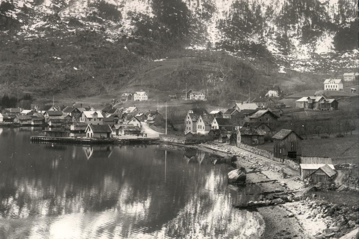 a black and white photo of a small town by a lake