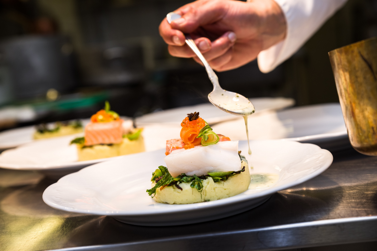 a person pouring sauce on food