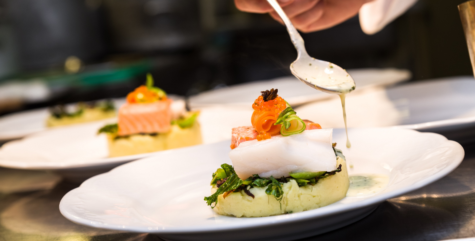 a person pouring sauce onto food on a plate