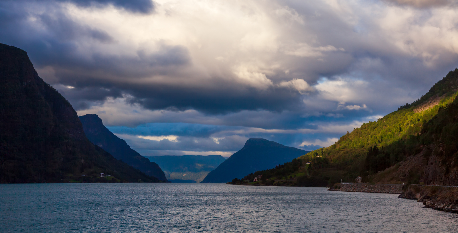 a body of water with mountains and clouds