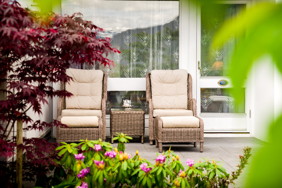 chairs on a patio with a table and plants