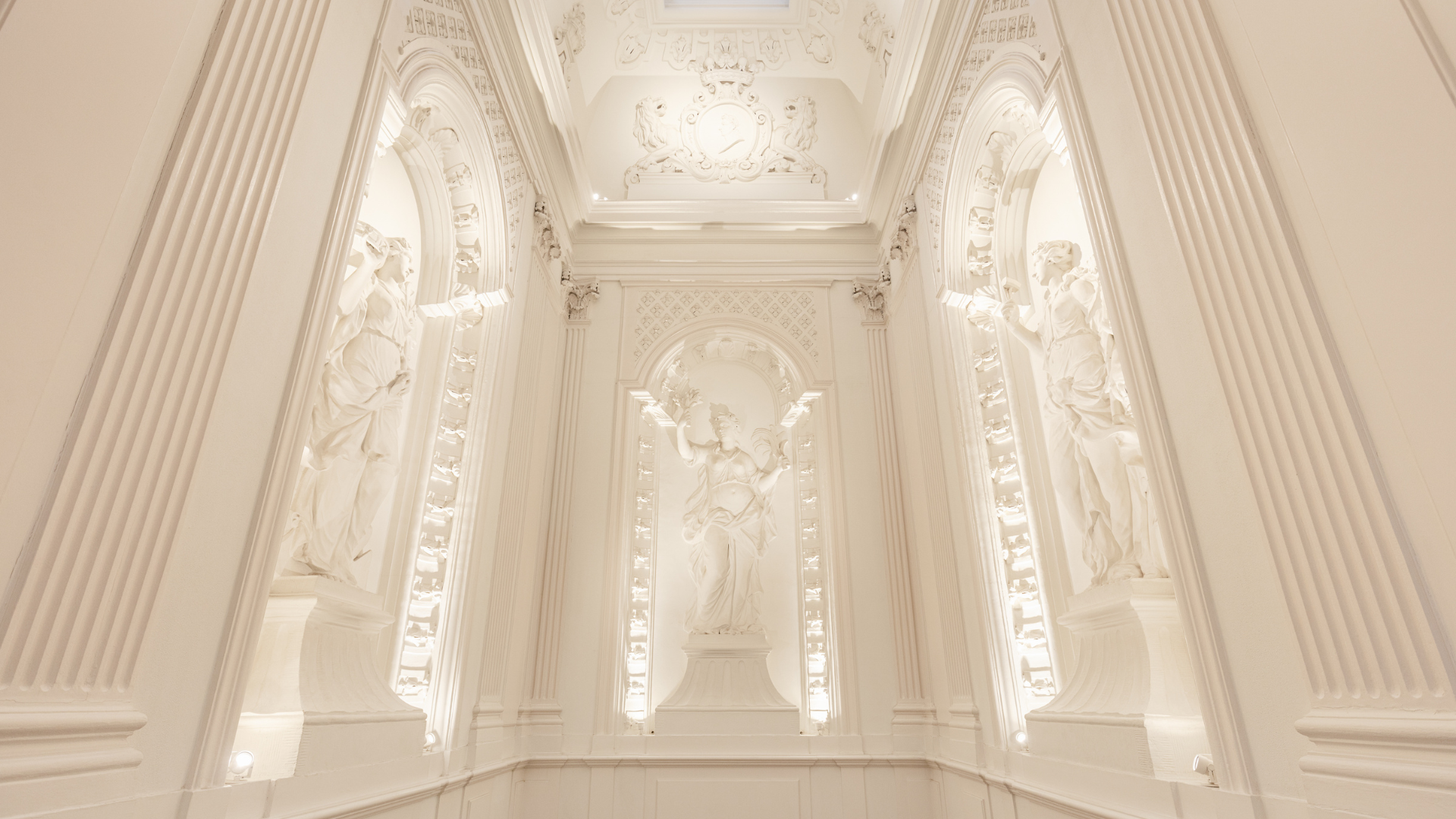a white room with statues and a skylight