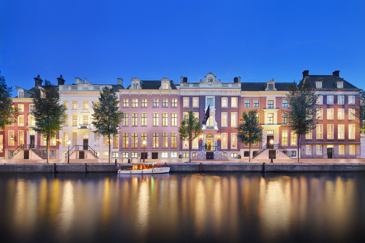 a row of buildings with trees and a boat in the water