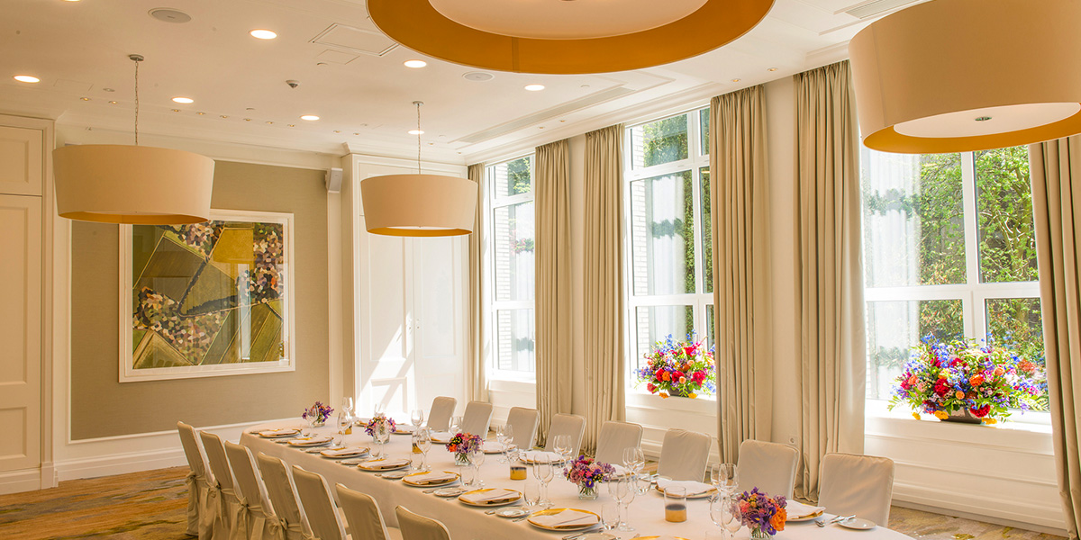 a long table with white chairs and flowers