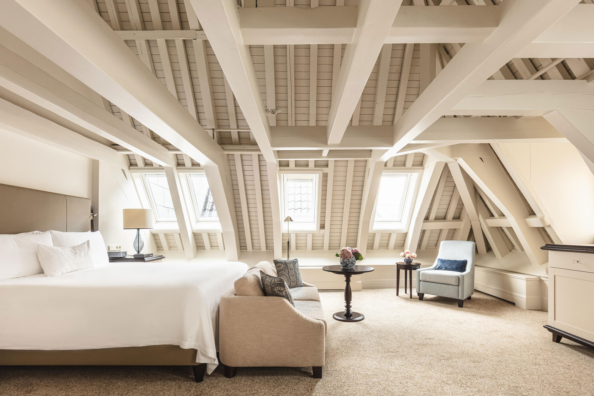 a bedroom with a bed and chairs in a attic