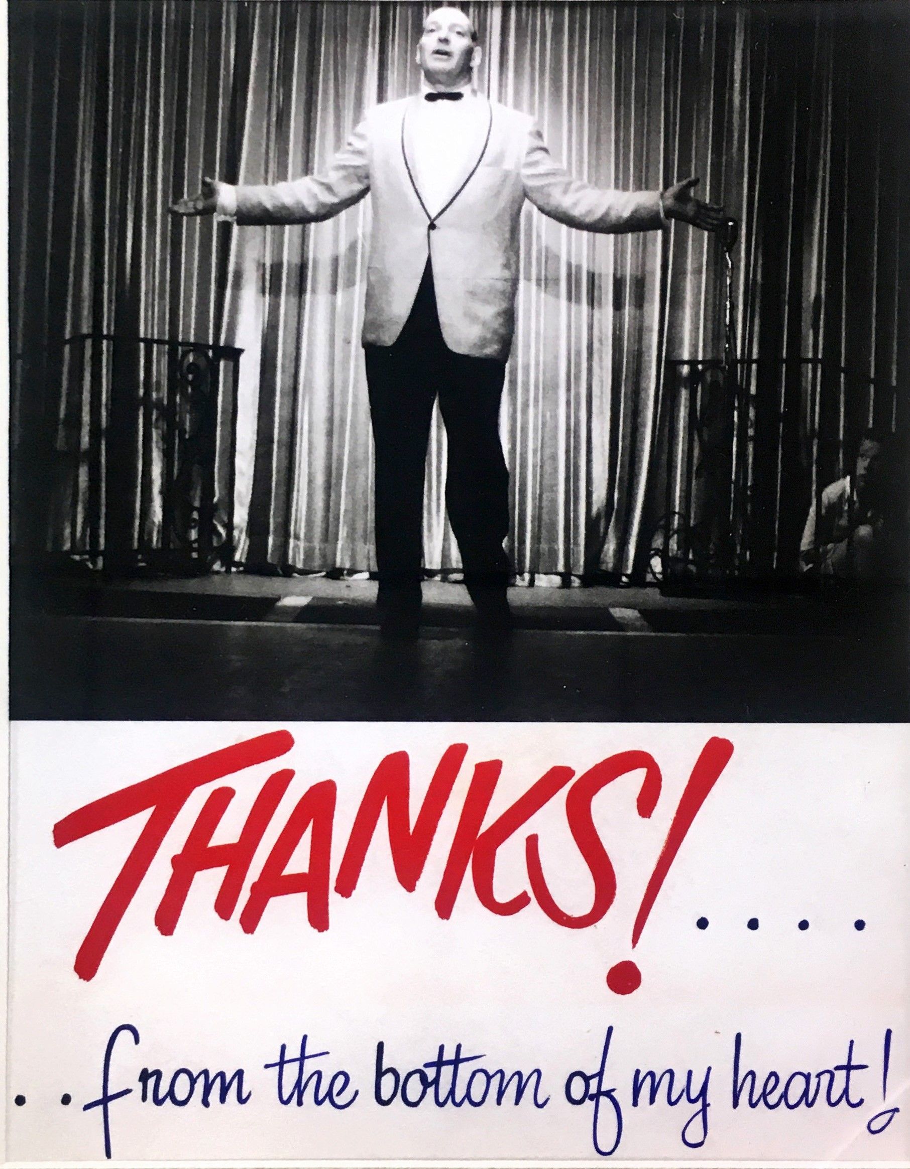 a man standing on a stage with his hands up